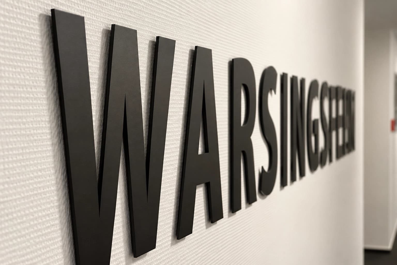 Nahaufnahme des schwarzen Schriftzugs WARSINGSFEHN an strukturierter Wand